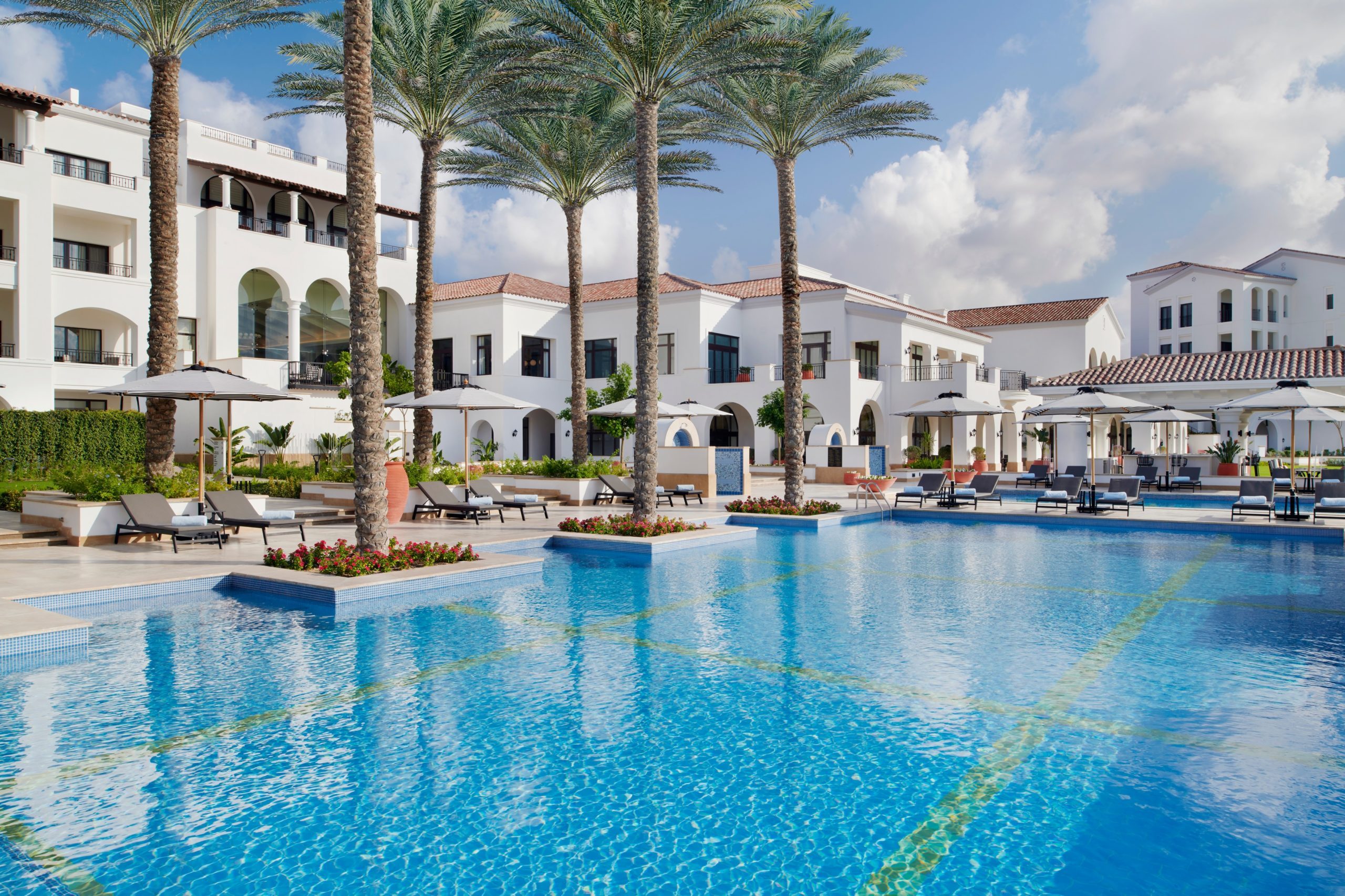 Swimming pool surrounded by palm trees and villas at Address Marassi Golf Resort